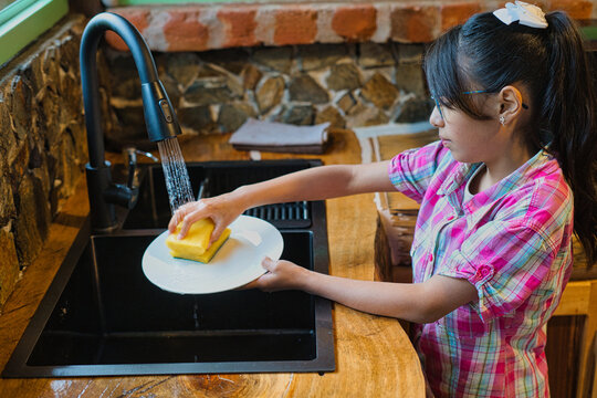 Young girl washing dishes in rustic kitchen