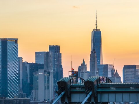 Aerial view of the iconic One World Trade Center piercing the sunset, framed by the sturdy architecture of the Williamsburg Bridge, New York, New York, United States.