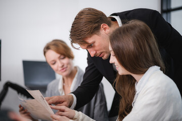 Professional business colleagues discussing and reviewing a printed document during an office meeting. Corporate teamwork and consultation concept.