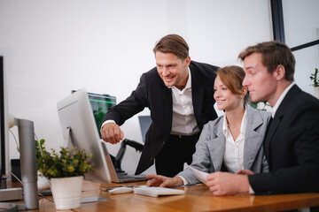 Smiling business professionals working together and analyzing information on a computer in a modern office environment.