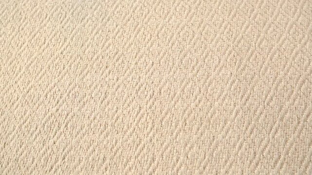 Natural beige textured fabric with repeating diamond pattern close up overhead view