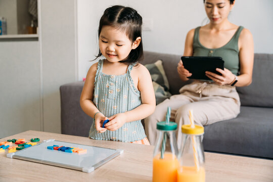 Girl playing with alphabet blocks while mother nearby
