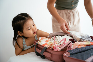 Adult packing suitcase under the gaze of the child