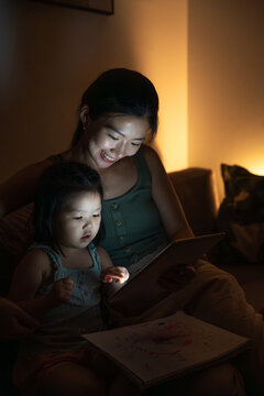 Mother and daughter sharing digital stories during bedtime