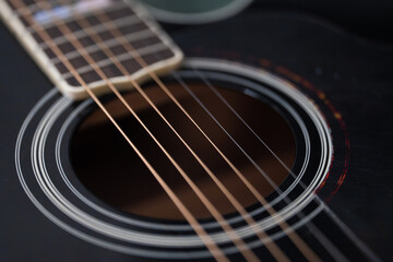 Close-up detail of acoustic guitar strings, showing metal texture and warm wooden tones. Musical...