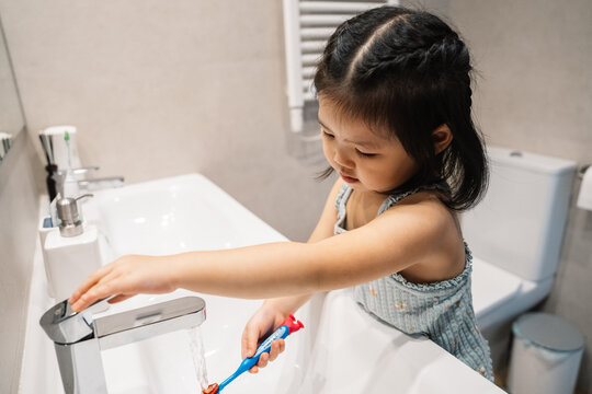 Child learning to brush teeth at bathroom sink