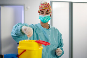Female doctor in surgical scrubs handles medical waste