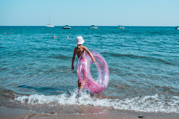 Girl on beach with swim ring during summer beach holiday.
