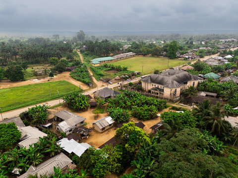 Aerial view of buildings and lush greenery blending with earth-toned structures under a soft, overcast sky, Khana, Rivers, Nigeria.