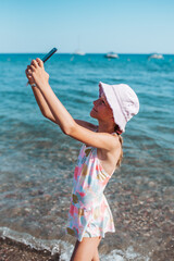 Girl taking selfie on beach with smartphone, summer beach holiday.