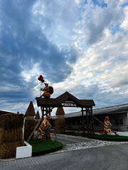 Obraz premium Dairy farm entrance with cow statues archway hay bales and balloon cows at the gate