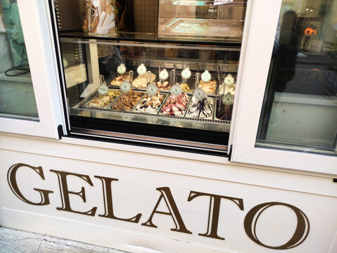 Rome, Italy - January 12, 2026: Gelato display case featuring various flavors and toppings in a shop window with the word "GELATO" prominently displayed on the exterior