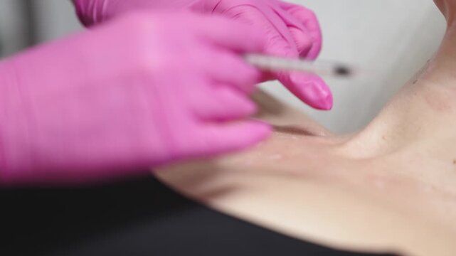 Skilled technician administering cosmetic treatment with a syringe on the shoulder area, showcasing precise technique and careful application of dermal filler in a beauty clinic setting