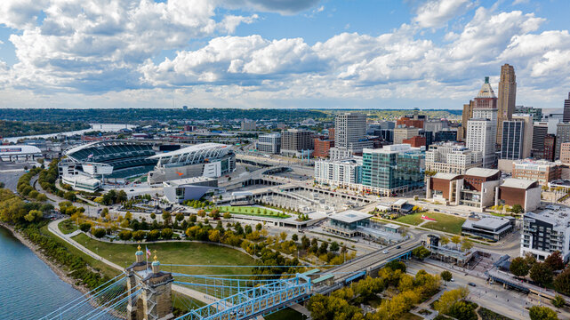 Aerial view of the Roebling Suspension Bridge, the Bengals' stadium, and the city's modern skyline under a vast sky, Cincinnati, Ohio, United States.