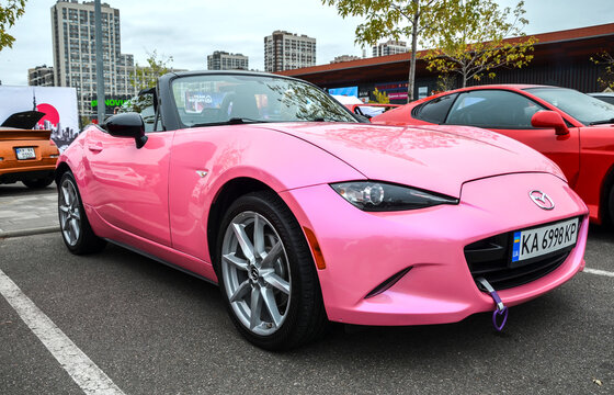 Custom pink fourth generation (ND) Mazda MX-5 Miata with soft top, identifiable by its sleek Kodo design elements