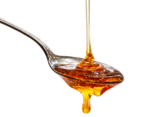 Thick golden amber honey pouring onto a classic silver spoon, the viscous sweet liquid swirling beautifully as it fills the utensil and drips off the side in a rich stream