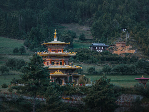 Aerial view of the Guru Nangsid Zilnon Phodrang temple nestled amid verdant hills, its golden roofs gleaming against the deep green forests, Mebartsho, Bhutan.