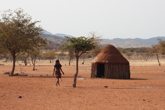 African woman from the Himba tribe walking towards her traditional hut