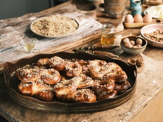 Warm and inviting scene showcases a wooden platter filled with freshly baked sweet pretzels, topped with chopped nuts. Surrounding ingredients hint at a joyful baking experience