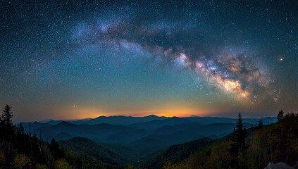 Fototapeta premium Vast, starry night sky arches over silhouetted mountain ranges