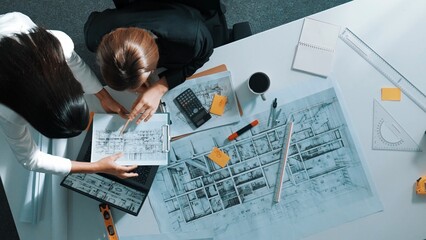 Top view of businesswoman hand blueprint to engineer sitting at meeting table with project plan, equipment and safety helmet. Aerial view of manager explain about building construction. Alimentation.