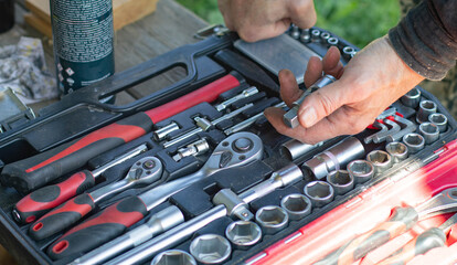 Hand preparing to use a screwdriver from a professional tool kit featuring diverse wrench sockets, essential for home, automotive, or general repair projects