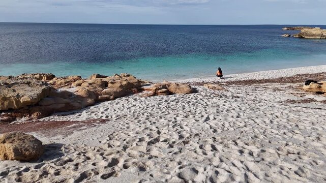 Brunette woman by the sea in winter at Is Arutas Beach, Sardinia, Italy