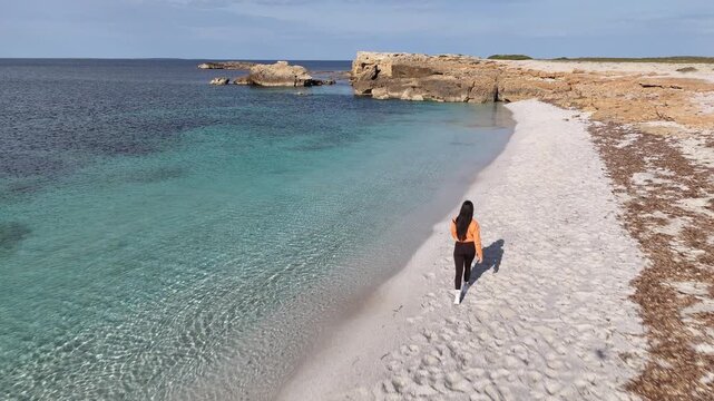 Brunette woman by the sea in winter at Is Arutas Beach, Sardinia, Italy