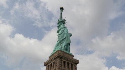 Statue of Liberty on Liberty Island, New York, United States. Blue cooper monument, symbol of democracy and patriotism near Manhattan, NYC USA. Clouds on sky. American independence. Torch and crown.