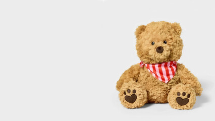 Obraz premium Brown stuffed bear with striped bandana on copy-space background.