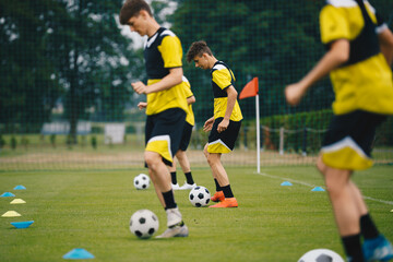 Youth Sports Player Running on Training Field and Kicking Balls. Junior Football Club Practice Session. Teenagers in Soccer Training Sportswear. Sports Educational Equipment