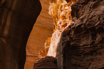 Exploring the canyon with sunlight shining on stone walls and cliffs. Petra, Jordan.