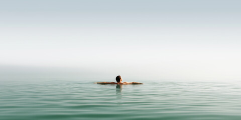 Fototapeta premium Person floating on back in calm open water finding peace, relaxation, and embracing solitude under a clear sky