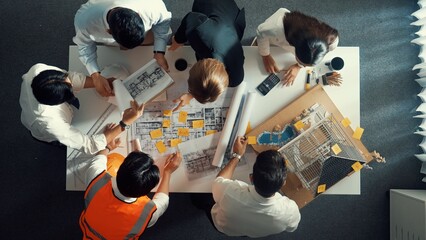 Top down view of skilled engineer team talking while measuring house model. Aerial view of group of...