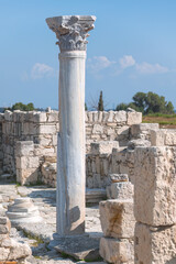 Kourion archaeological site showing standing column and historical remains under blue sky