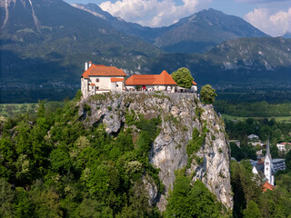 Aerial view of Bled Castle overlooking Lake Bled, Slovenia. Medieval fortress on a cliff captured by drone, surrounded by alpine landscape and clear blue water. Famous European travel destination and 
