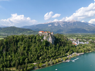 Aerial view of Bled Castle overlooking Lake Bled, Slovenia. Medieval fortress on a cliff captured by drone, surrounded by alpine landscape and clear blue water. Famous European travel destination and 