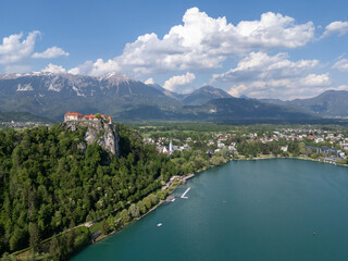 Aerial view of Bled Castle overlooking Lake Bled, Slovenia. Medieval fortress on a cliff captured by drone, surrounded by alpine landscape and clear blue water. Famous European travel destination and 