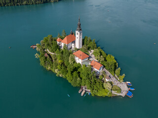 Aerial drone view of Bled Island with the Church of the Assumption in the middle of Lake Bled, Slovenia. The iconic island church is surrounded by turquoise alpine waters and forested mountains. Famou