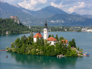 Aerial drone view of Bled Island with the Church of the Assumption in the middle of Lake Bled, Slovenia. The iconic island church is surrounded by turquoise alpine waters and forested mountains. Famou
