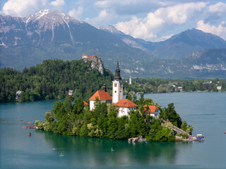 Aerial drone view of Bled Island with the Church of the Assumption in the middle of Lake Bled, Slovenia. The iconic island church is surrounded by turquoise alpine waters and forested mountains. Famou