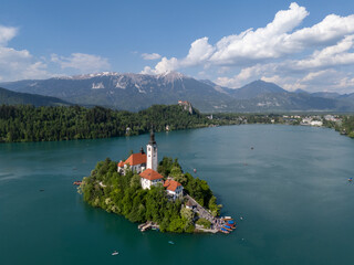 Aerial drone view of Bled Island with the Church of the Assumption in the middle of Lake Bled, Slovenia. The iconic island church is surrounded by turquoise alpine waters and forested mountains. Famou