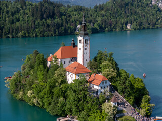 Aerial drone view of Bled Island with the Church of the Assumption in the middle of Lake Bled, Slovenia. The iconic island church is surrounded by turquoise alpine waters and forested mountains. Famou