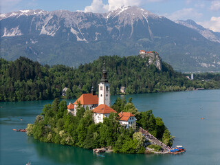 Aerial drone view of Bled Island with the Church of the Assumption in the middle of Lake Bled, Slovenia. The iconic island church is surrounded by turquoise alpine waters and forested mountains. Famou