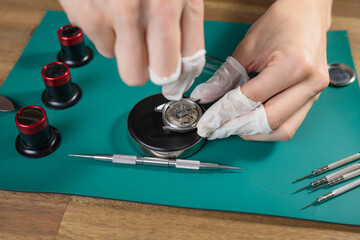 A professional watchmaker uses fine tools to assemble and adjust a luxury mechanical watch movement on a clean workbench.
