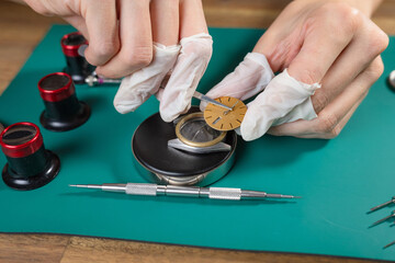 A skilled watchmaker assembles a luxury mechanical watch movement using fine tools and attention to detail on a clean workbench.