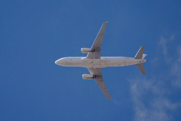 Obraz premium Underside view of a white passenger plane in flight