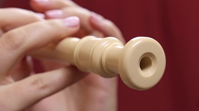 Woman holding in her hands and playing block flute (recorder) musical instrument