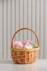 Wicker Easter Basket with Pastel Eggs and Flowers. Soft Spring Decor