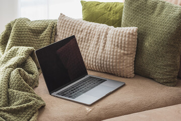 Laptop on Cozy Sofa with Textured Pillows and Blanket. Relaxed Home Workspace